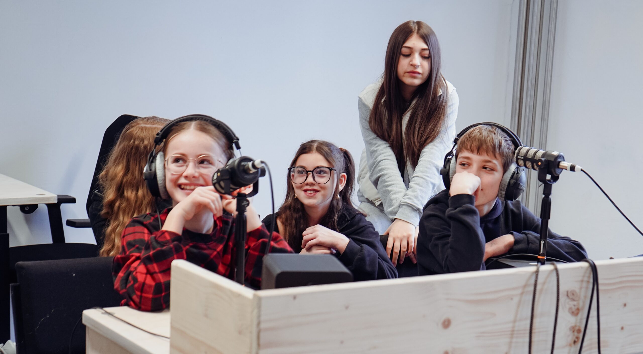 Kinder sitzen beisammen und nehmen einen Podcast auf