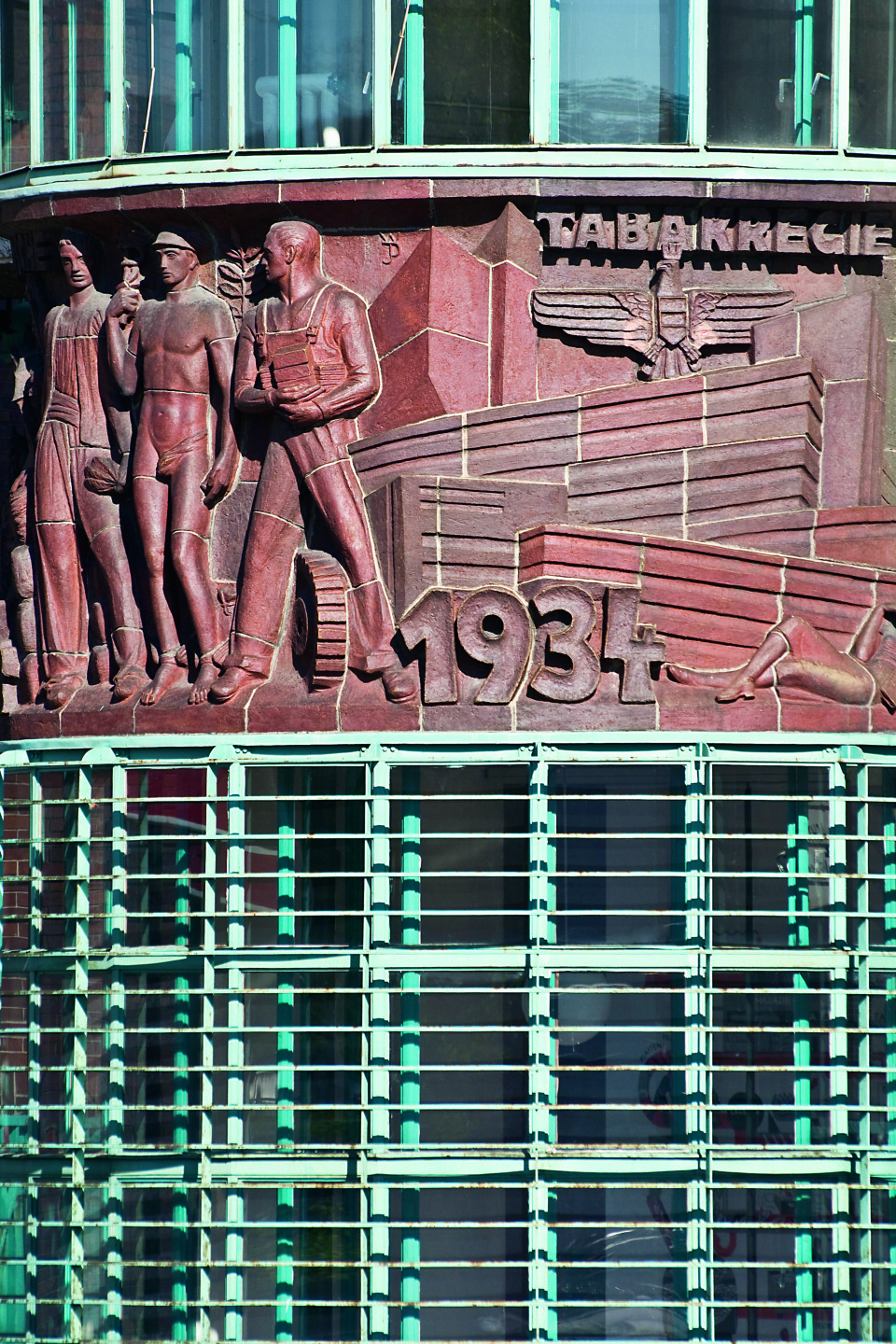 Haupttor der Tabakfabrik, durch die Bahn und Autos einfuhren. Am Vorbau prangt das Jubiläums-Gedenkrelief der österreichischen Tabakregie aus 1934. Der akademische Bildhauer Prof. Wilhelm Fraß entwarf es aus hartgebranntem Klinker.