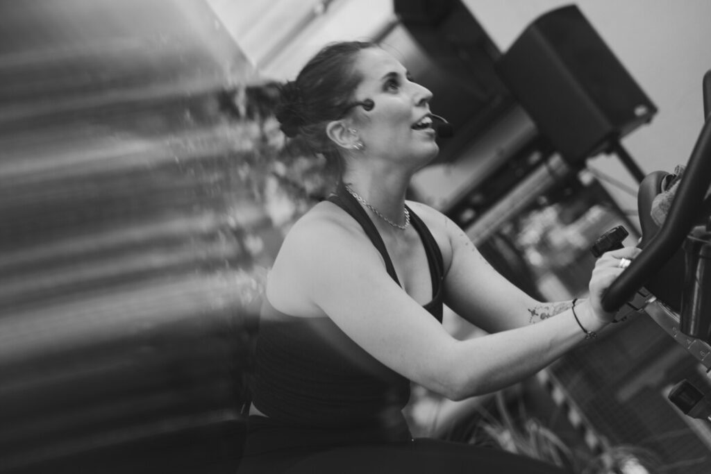 Eine Dame sitzt auf einem Spinning Bike und gibt den Ton für das Glow Ride Event an.