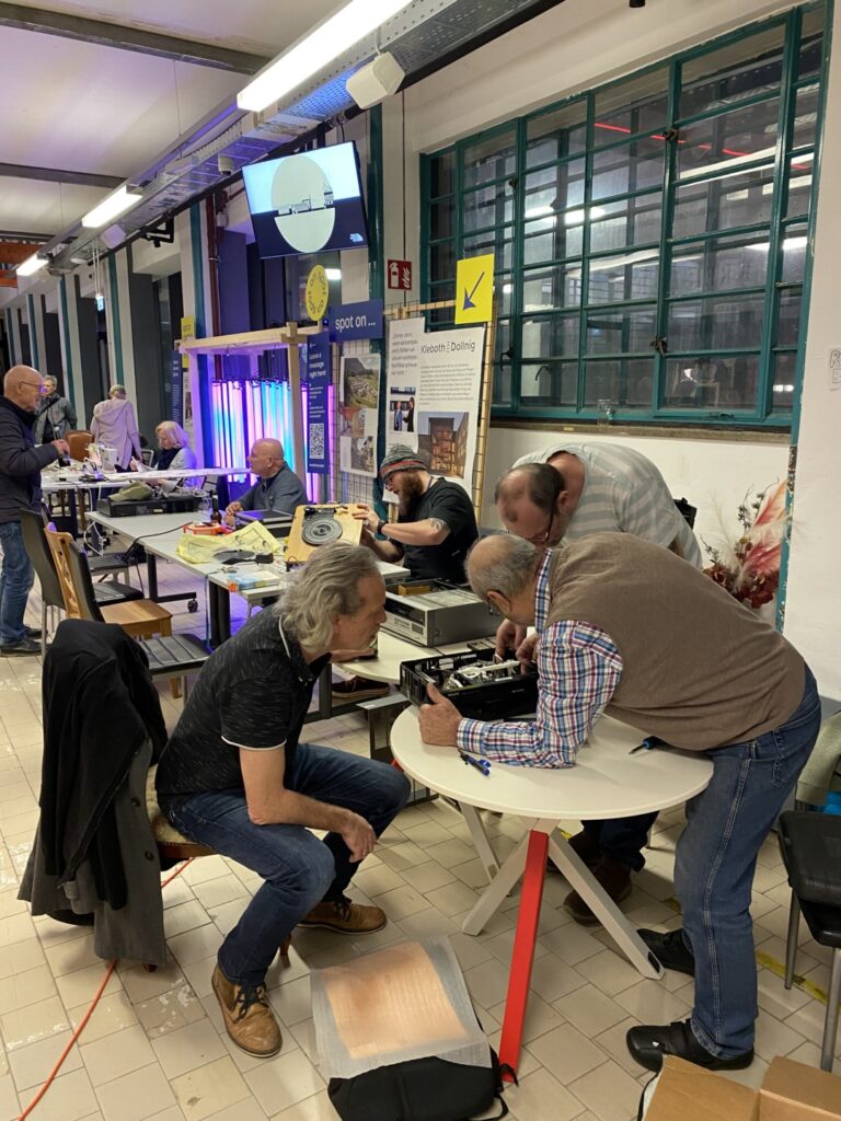 Eine Kleingruppe hilft beim Repair Café zusammen, um kaputte Teile wieder in Ordnung zu bringen.