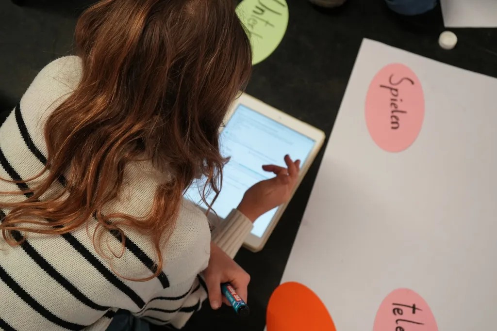 Ein Mädchen schaut auf einen Bildschirm/Tablet, während dem Cybersommer Angebot vom Innerversum.